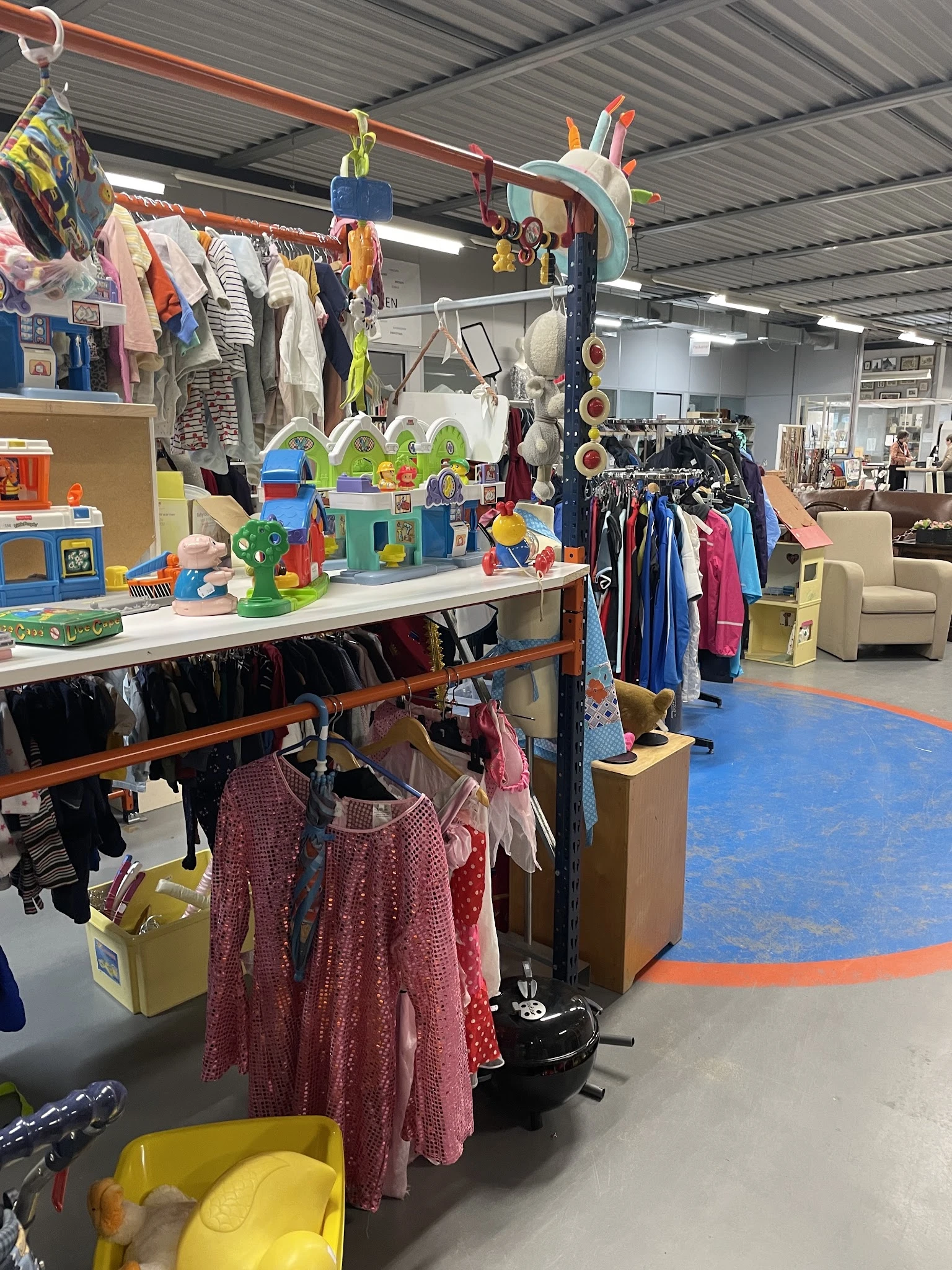 Kinderkleding en speelgoed uitgestald op tafels en rekken in de winkel