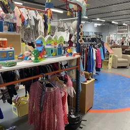 Kinderkleding en speelgoed uitgestald op tafels en rekken in de winkel