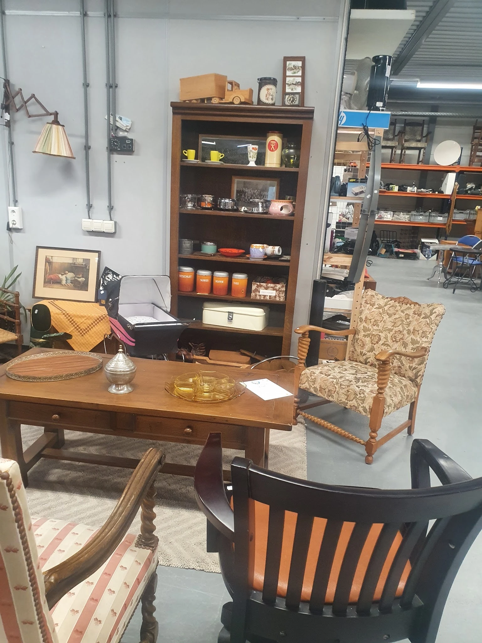 Winkelinterieur met houten bureau, fauteuil, boekenkast en diverse decoratieve items