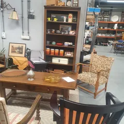 Winkelinterieur met houten bureau, fauteuil, boekenkast en diverse decoratieve items