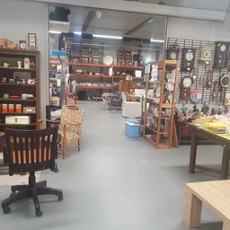 Overzicht van de winkelvloer met houten meubels, stellingen, een zwarte bureaustoel, diverse artikelen en decorstukken