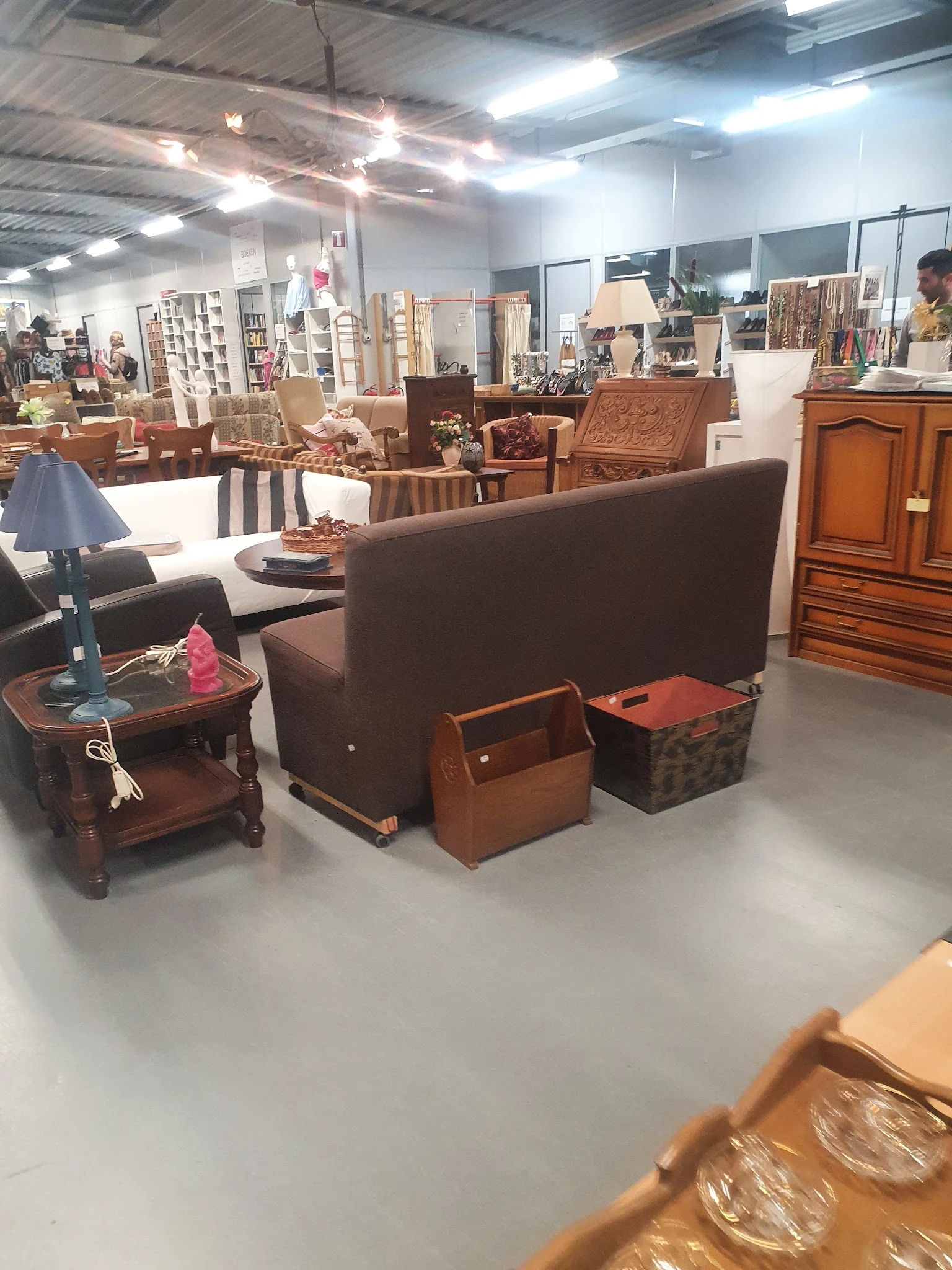 Meubels in de winkel: bruine fauteuil, houten tafels, houten kasten en opbergmanden.