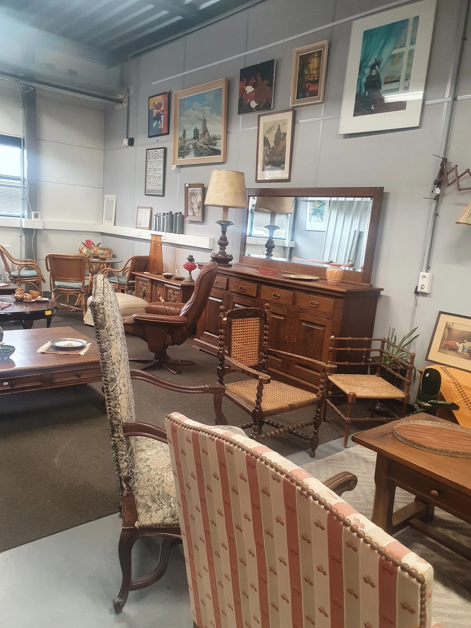 Interieur van kringloopwinkel met diverse meubels zoals houten kasten, stoelen en tafels