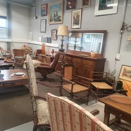 Interieur van kringloopwinkel met diverse meubels zoals houten kasten, stoelen en tafels
