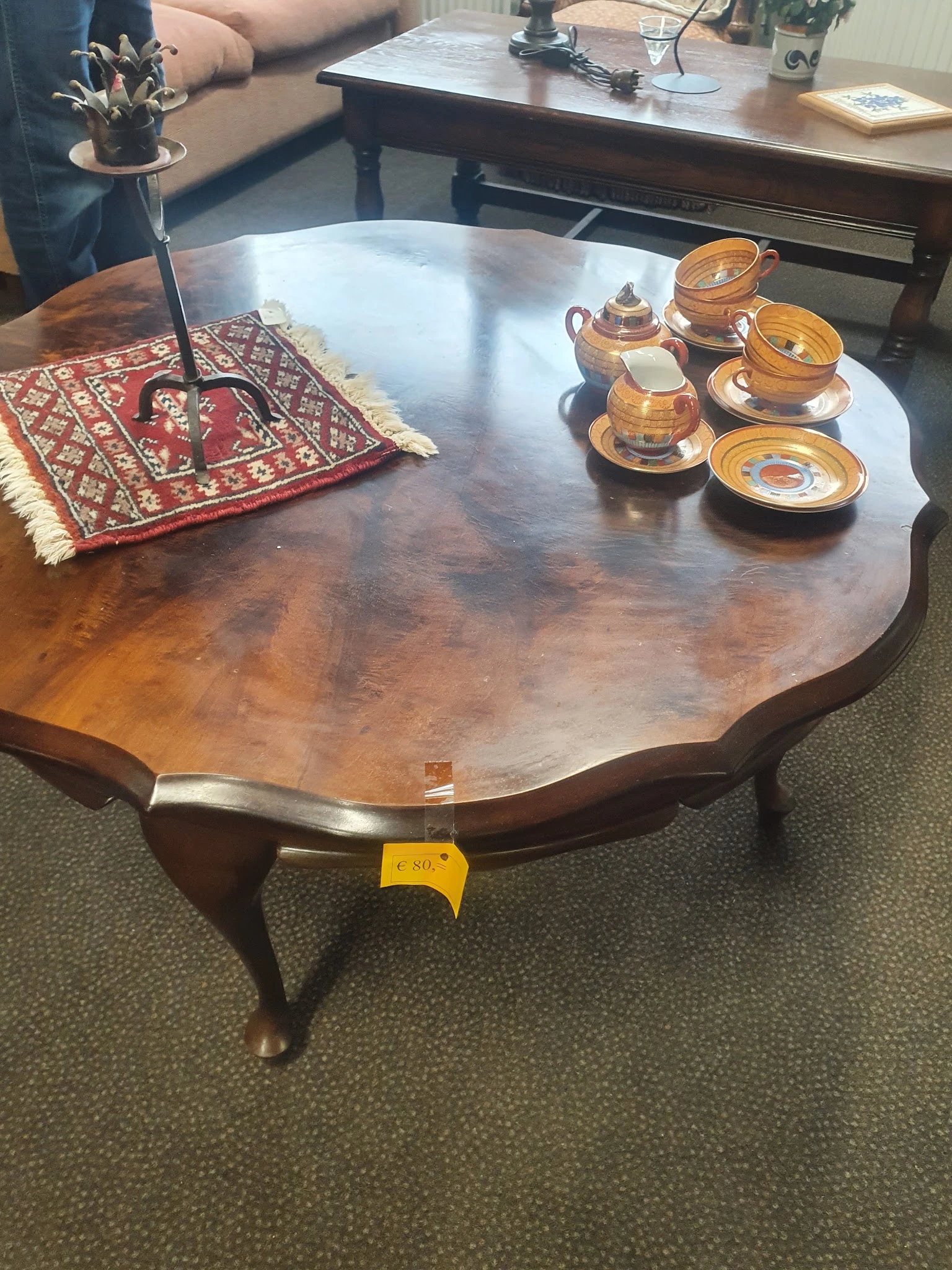 Houten tafel met golvende rand en twee houten theepotten met kopjes op witte schotels