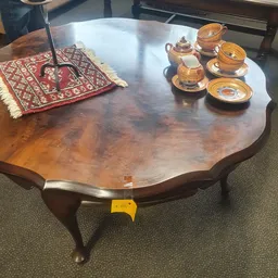 Houten tafel met golvende rand en twee houten theepotten met kopjes op witte schotels