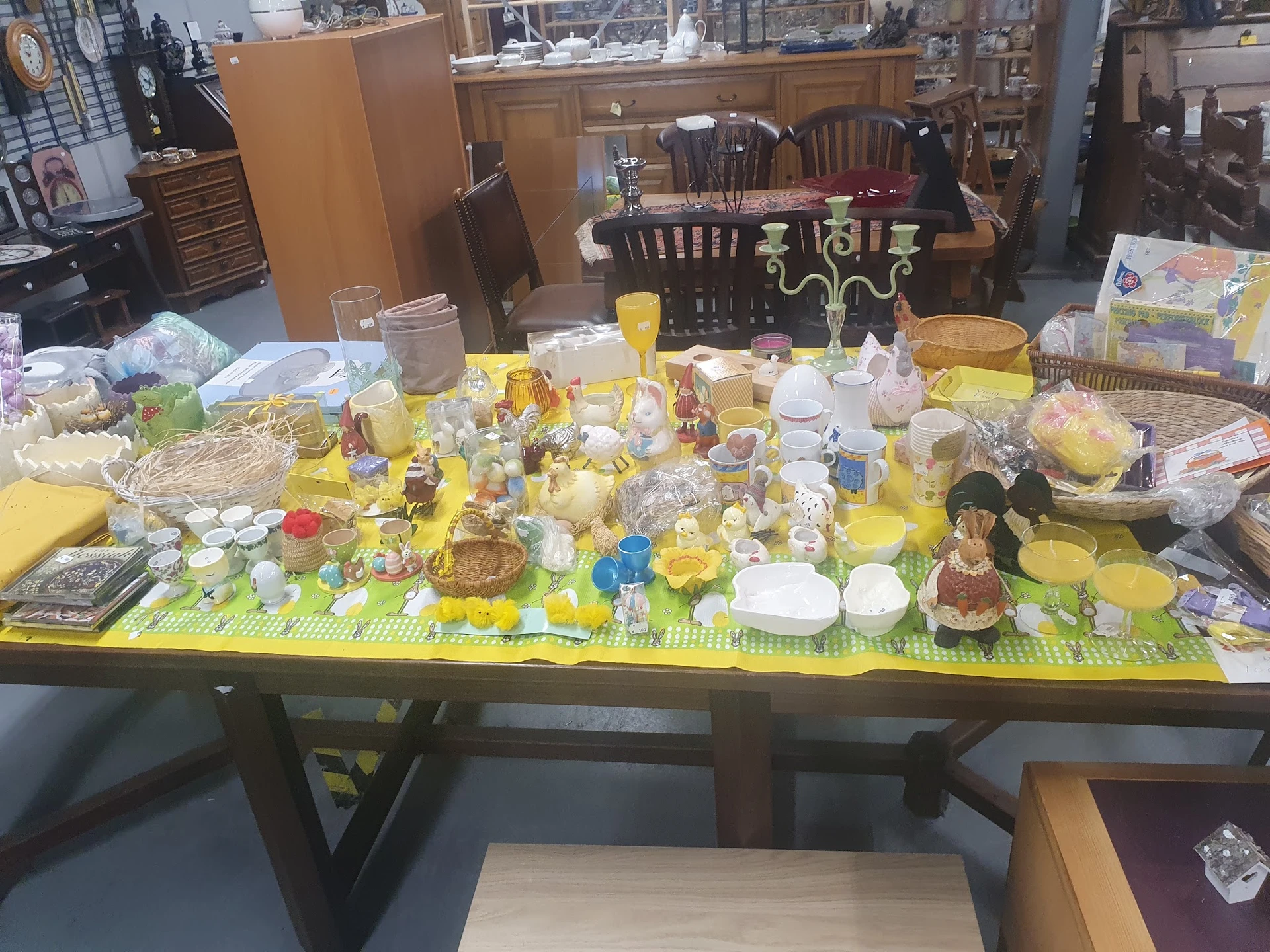 Tafel vol geel serviesgoed, glazen, decoraties en huishoudartikelen op gele ondergrond
