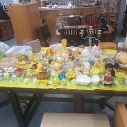 Tafel vol geel serviesgoed, glazen, decoraties en huishoudartikelen op gele ondergrond