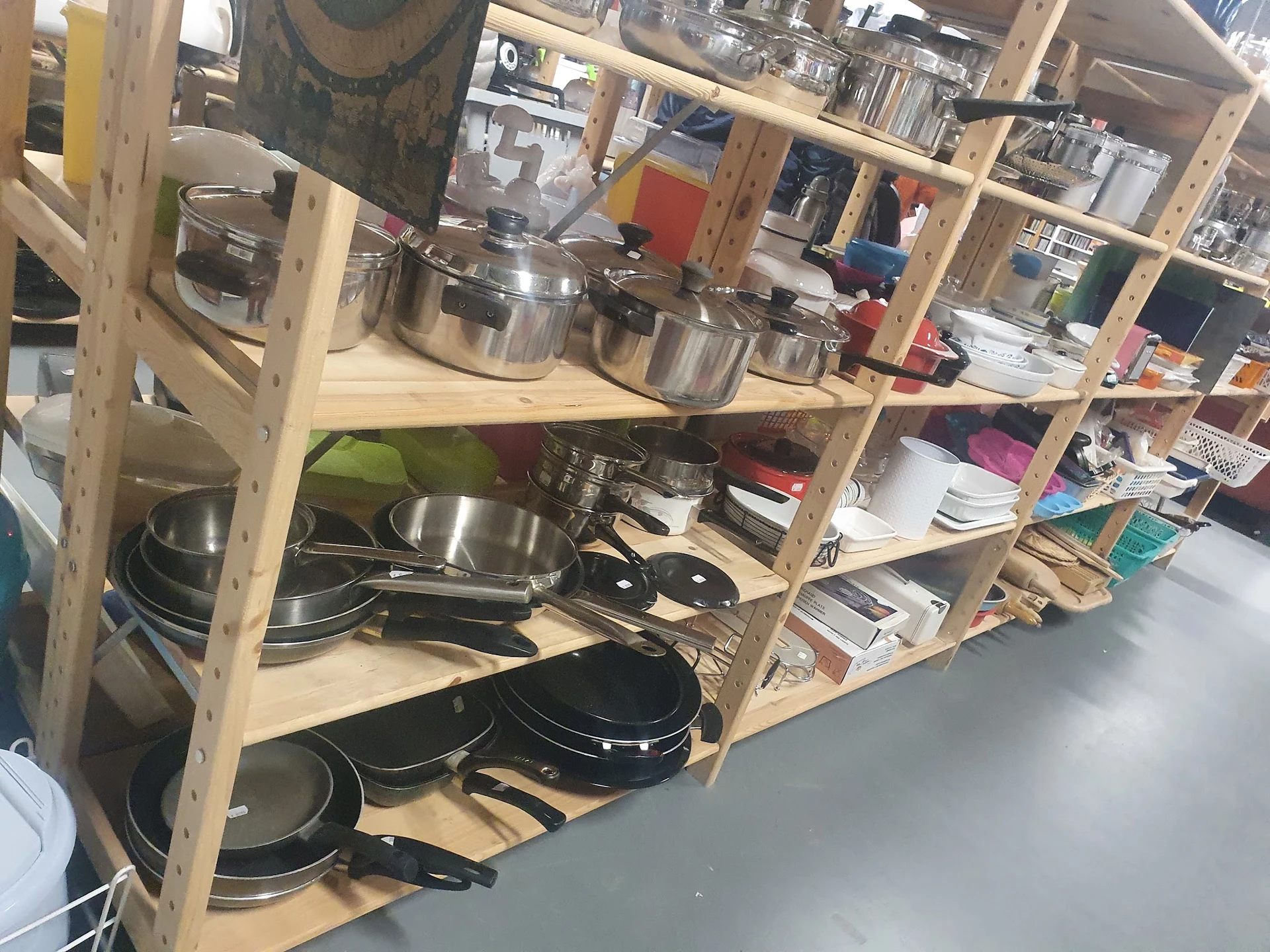 Houten stellingkast met diverse kookgerei: pannen, potten, wokpannen en andere keukengerei netjes uitgestald.