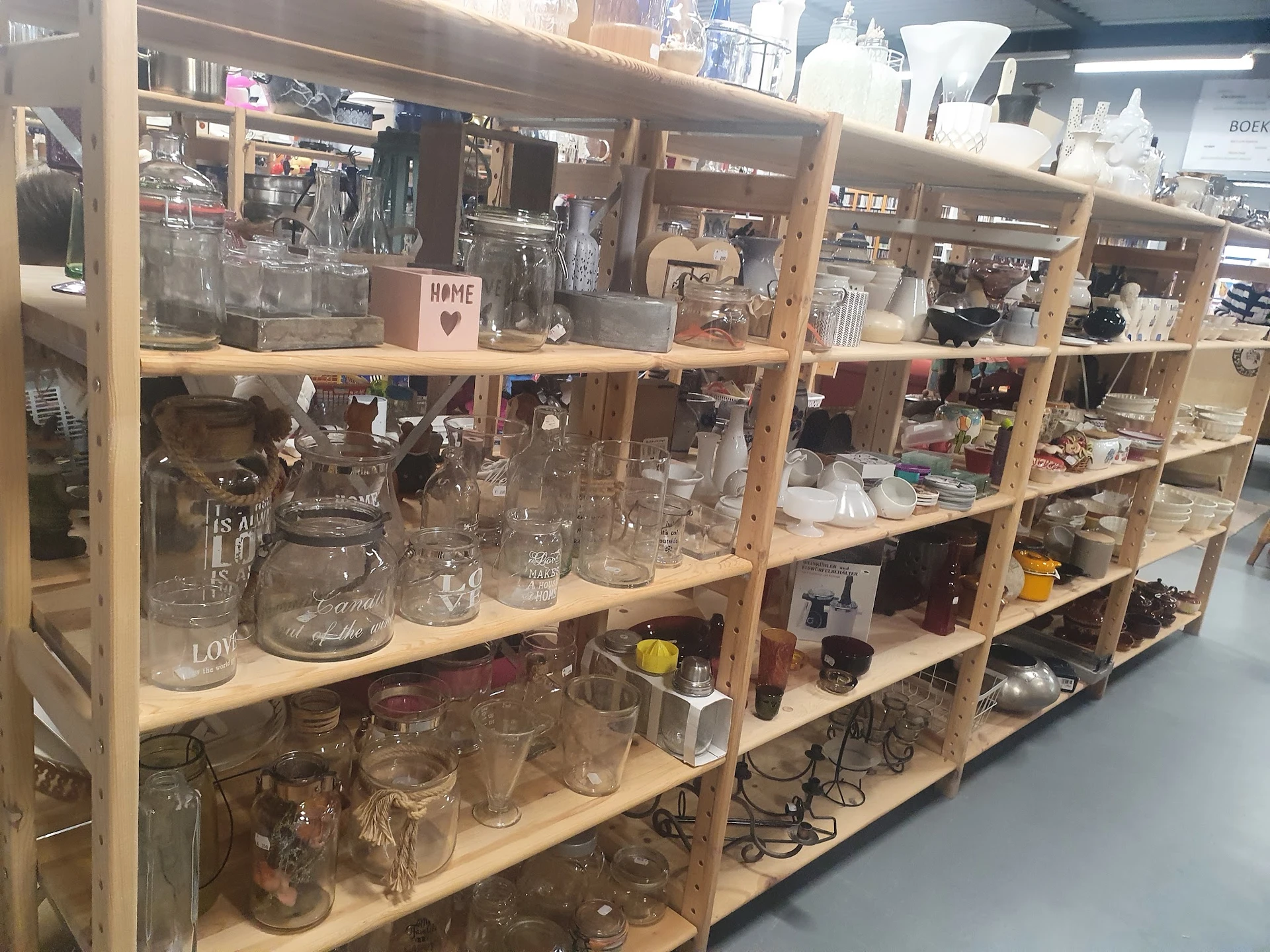 Houten stellingkast met glazen potten, flesjes en huishoudartikelen in verschillende maten