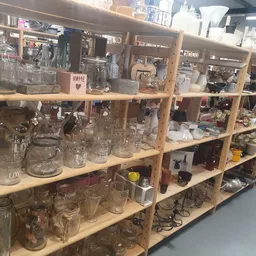 Houten stellingkast met glazen potten, flesjes en huishoudartikelen in verschillende maten