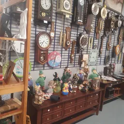 Antieke klokken, beeldjes en huishoudelijke artikelen op een houten dressoir en aan de muur