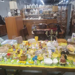 Uitgestalde gele huishoudelijke artikelen, servies en keukenbenodigdheden op een tafel in de kringloopwinkel