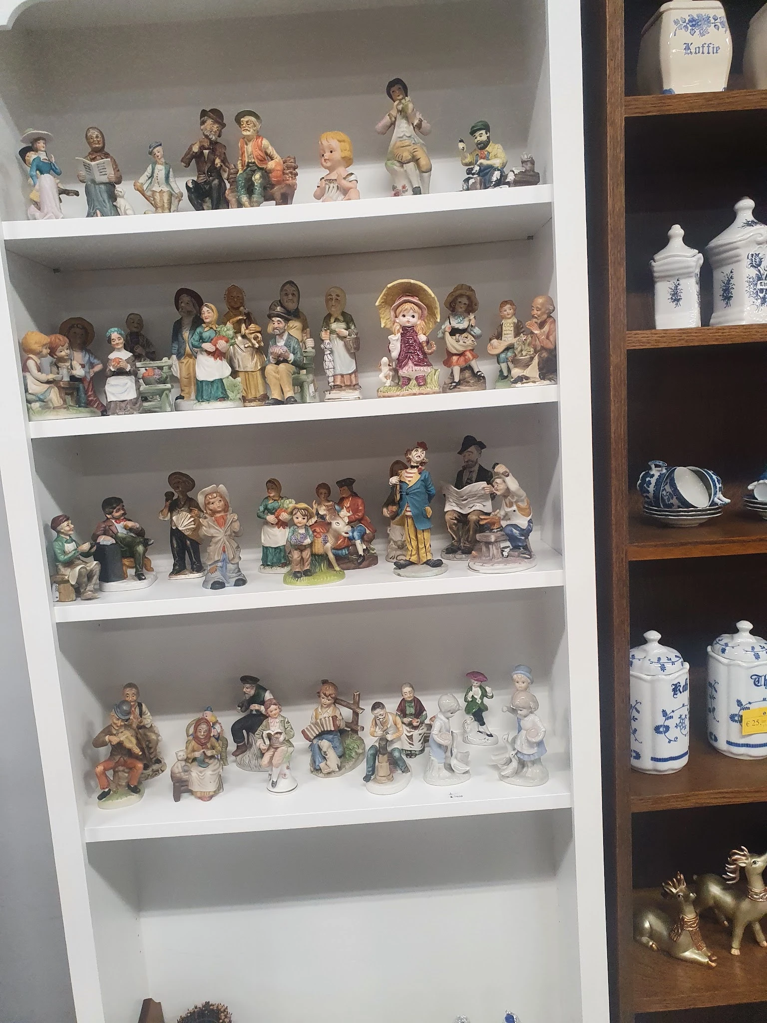 Drie planken met verzameling keramische beeldjes en decoratieve porseleinen objecten