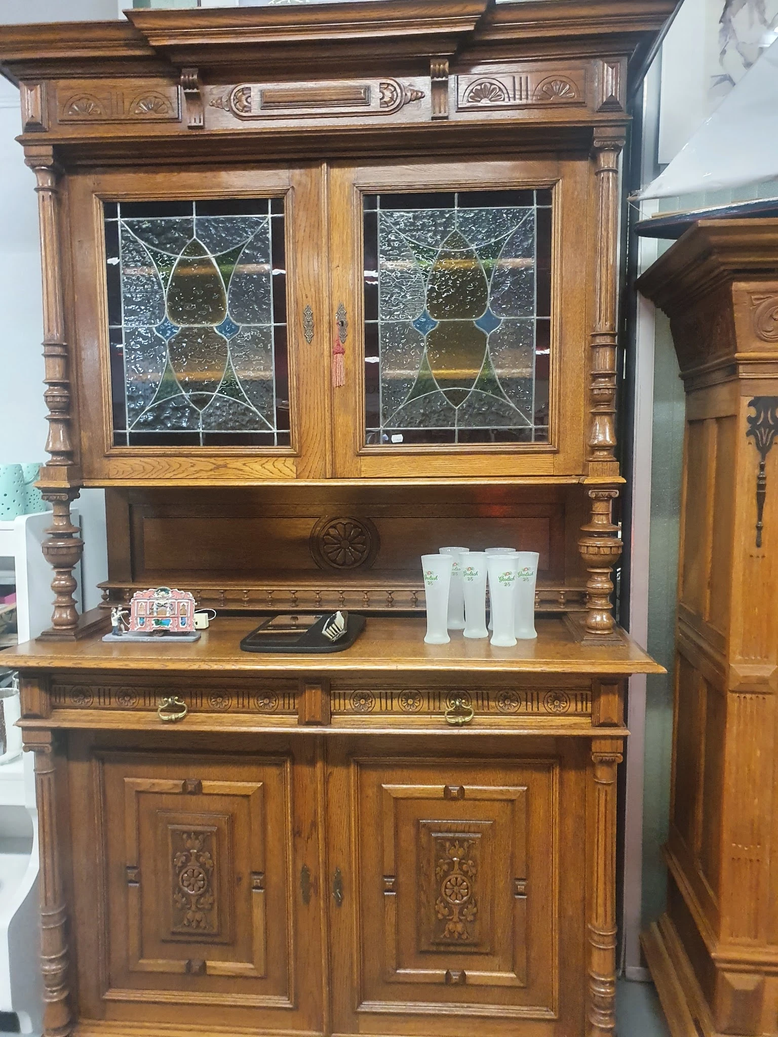Antieke houten vitrinekast met geslepen glasdeuren en decoratieve elementen