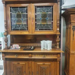 Antieke houten vitrinekast met geslepen glasdeuren en decoratieve elementen