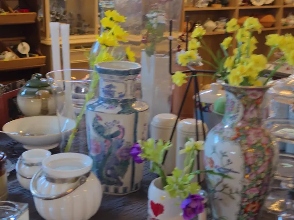 Diverse keramische voorraadpotten, servies en bloemenvazen met gele en paarse bloemen op een tafel