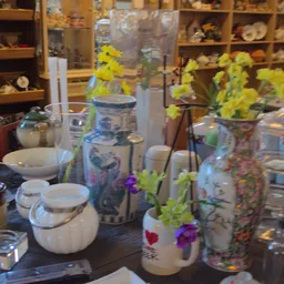 Diverse keramische voorraadpotten, servies en bloemenvazen met gele en paarse bloemen op een tafel