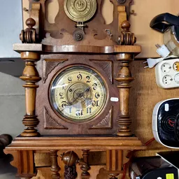 Houten staande klok met ronde wijzerplaat en decoratieve zuilen aan beide zijden