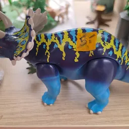 Kleurrijke speelgoedfiguur van een dinosaurus met blauwe poten en geel-zwart gemotiveerde rug