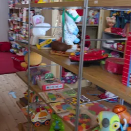 Speelgoed en vogelkooi op houten planken en in glazen vitrines met diverse speelgoedartikelen