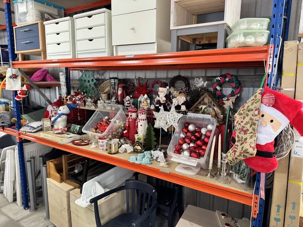 Stellingrek met kerstsieraden en decoraties, waaronder kerstballen, figuren en guirlandes