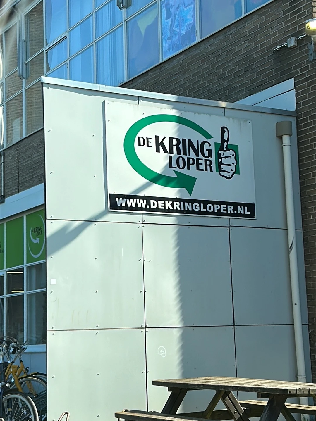 Gevel van kringloopwinkel De Kringloper met groen logo en website-adres