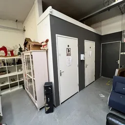 Binnenzicht van kringloopwinkel met witte kastjes, donkergrijze wanden en witte deuren
