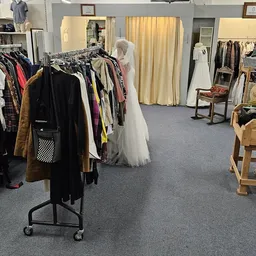 Winkelvloer met kledingrekken vol tweedehands kleding, mannequins en paskamers met gordijnen