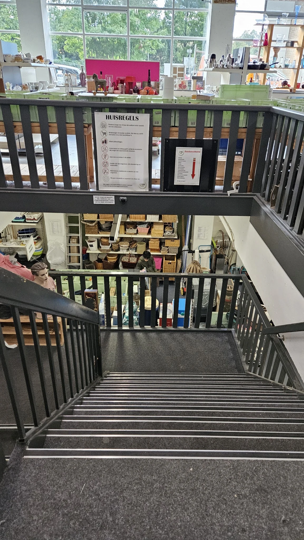 Overzicht van winkelinterieur met trappen, stellingen met dozen en opbergsystemen