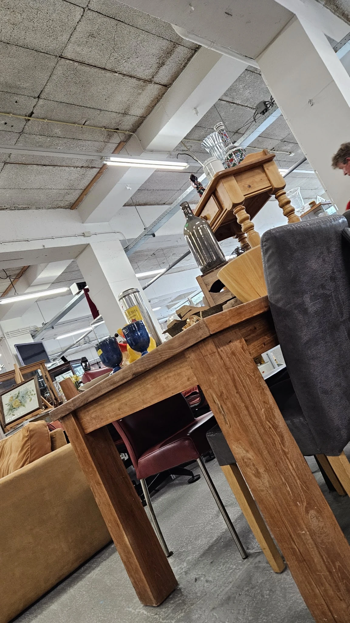 Winkelvloer met houten meubels, stellingen en diverse spullen in een kringloopwinkel
