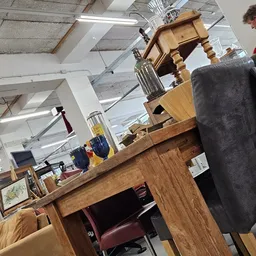 Winkelvloer met houten meubels, stellingen en diverse spullen in een kringloopwinkel