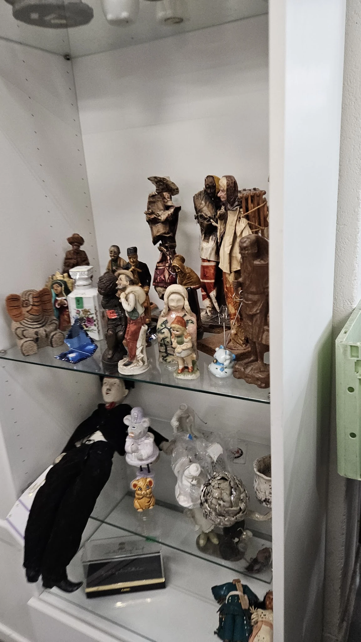 Glazen vitrine met diverse verzamelobjecten: beeldjes, poppen en decoratieve items