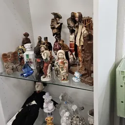 Glazen vitrine met diverse verzamelobjecten: beeldjes, poppen en decoratieve items