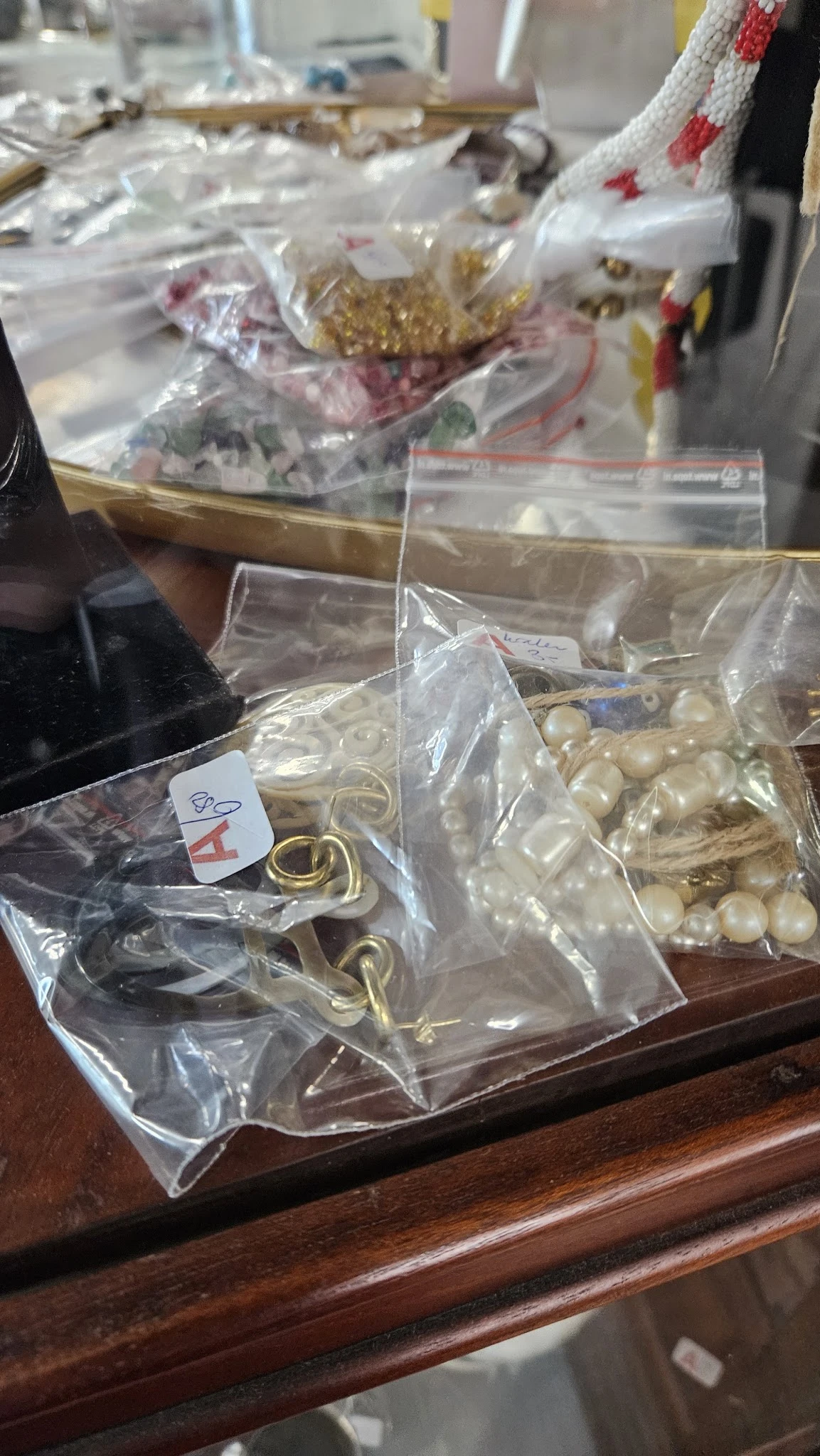 Zakjes met goudkleurige metalen ringen en parels in plastic verpakking