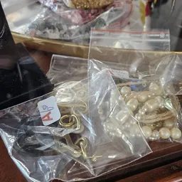 Zakjes met goudkleurige metalen ringen en parels in plastic verpakking