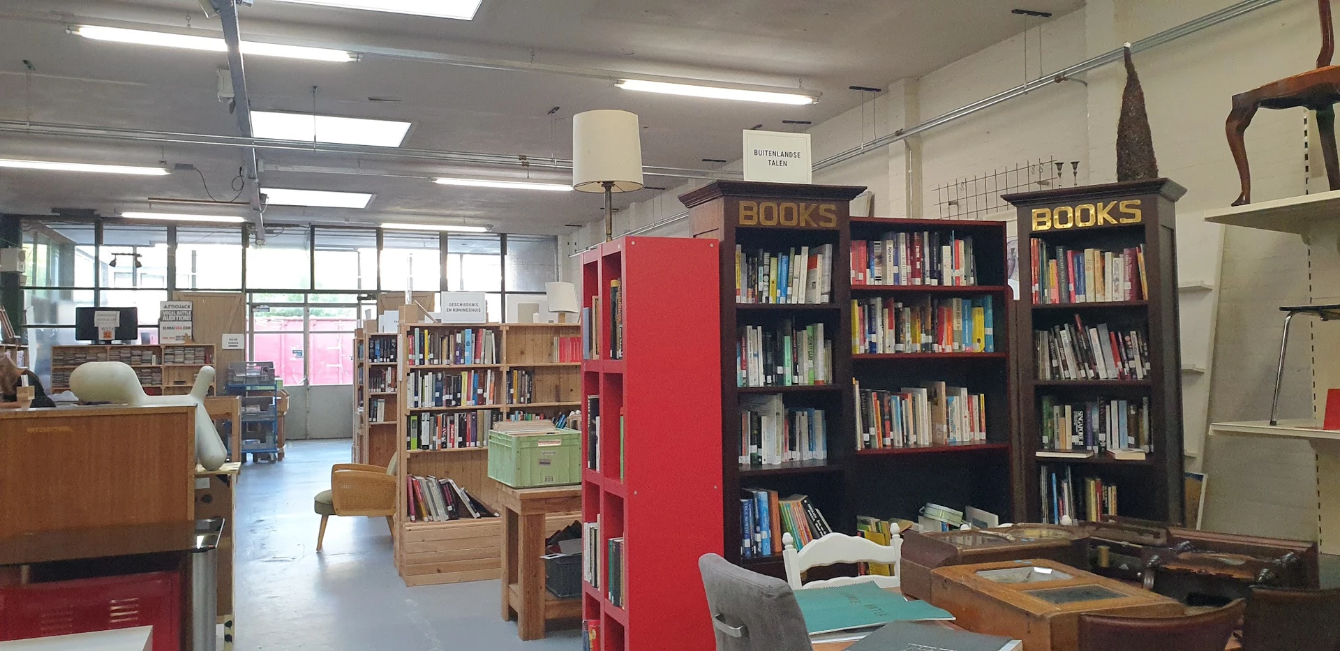 Boekenrekken en boekenkast in de winkel met rode en zwarte stellingen vol met tweedehands boeken