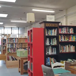 Boekenrekken en boekenkast in de winkel met rode en zwarte stellingen vol met tweedehands boeken