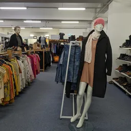 Winkelvloer met kledingrekken, etalagepop en schoenenrek in kringloopwinkel