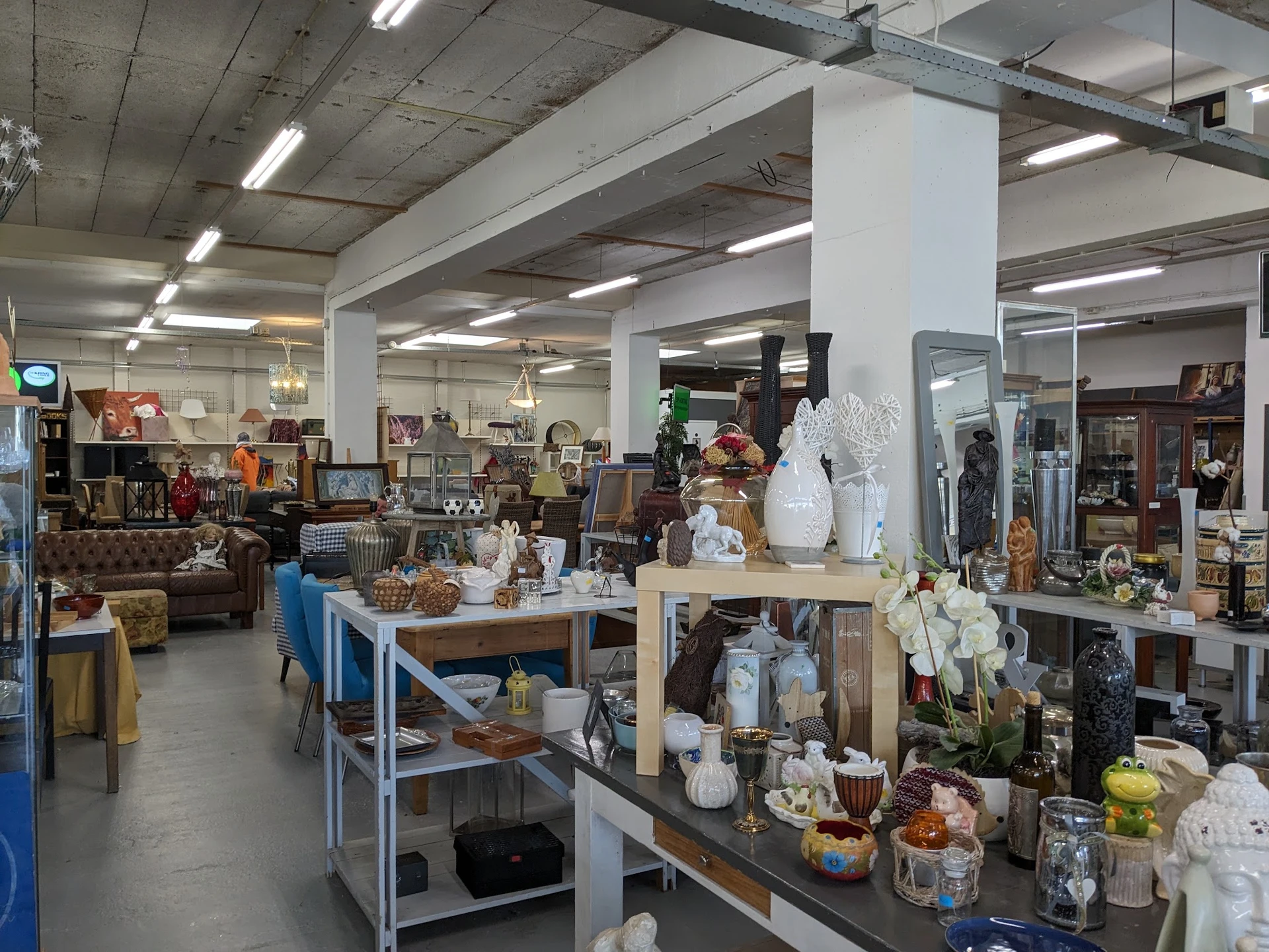 Winkelvloer van kringloopwinkel met tafels vol huishoudartikelen, decoratie en gebruikt goed
