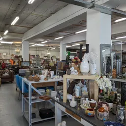 Winkelvloer van kringloopwinkel met tafels vol huishoudartikelen, decoratie en gebruikt goed