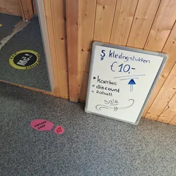 Whiteboard met handgeschreven advertentie voor 5 kledingstukken voor €10 met korting, rabat en sale