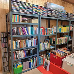 Zware stalen stellingen vol met tweedehands boeken, cd's en dvd's, georganiseerd per schap