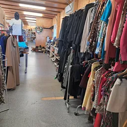 Rekken met tweedehands kleding, vooral zwarte en gekleurde jassen en jasjes, netjes uitgestald in de winkel