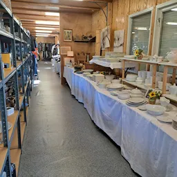Tafels met wit servies, borden en eetgerei uitgestald in de winkel