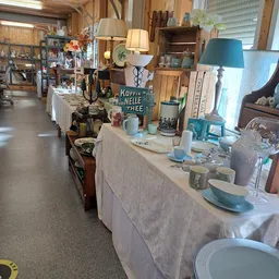 Uitgestalde huishoudartikelen en servies op witte tafels in de kringloopwinkel
