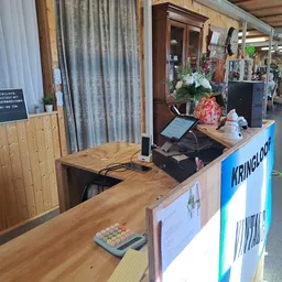 Balie met kassa en versiering in kringloopwinkel, op de achtergrond schappen en gordijnen