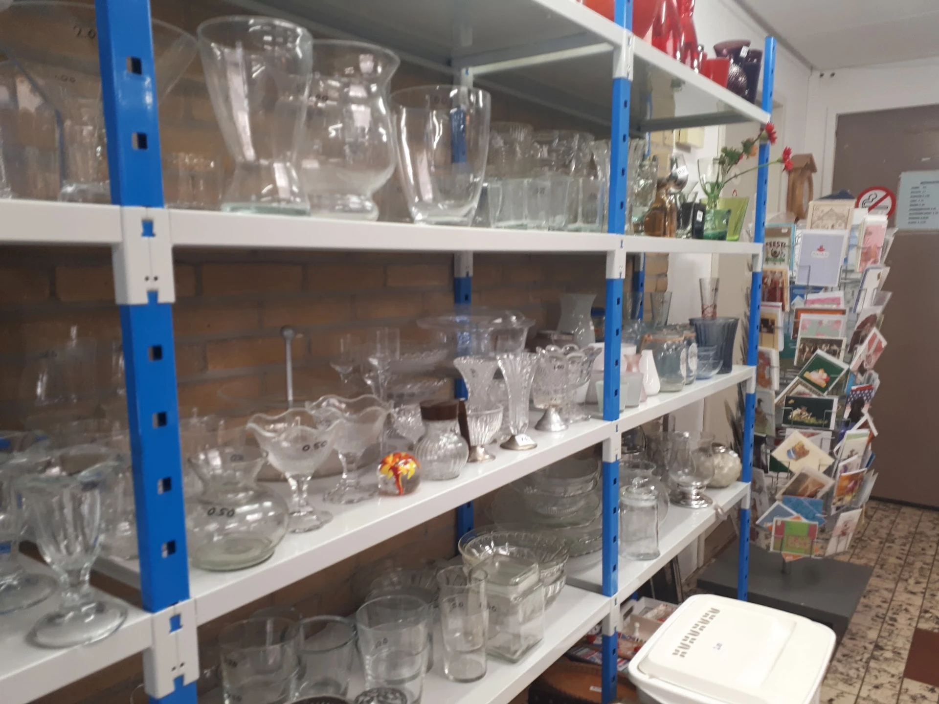 Stellingen met assortiment glazen, kannen en serviesgoed in verschillende maten en vormen
