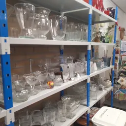 Stellingen met assortiment glazen, kannen en serviesgoed in verschillende maten en vormen