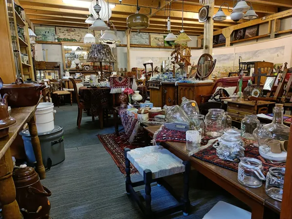 Winkelvloer vol met meubels, servies, glazen en diverse huishoudelijke artikelen op tafels en stellingen